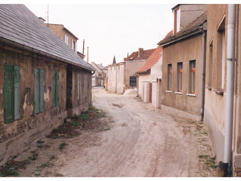 Die unbefestigte Straße Am Mühlenberg im Juli 1992 mit Blick in die Mühlenstraße.  Im Hintergrund ist die Kirchturmspitze der Kirche Maria Meeresstern zu sehen.